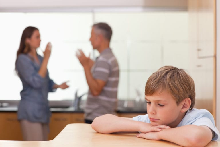 Sad little boy hearing his parents having am argument in a kitchen